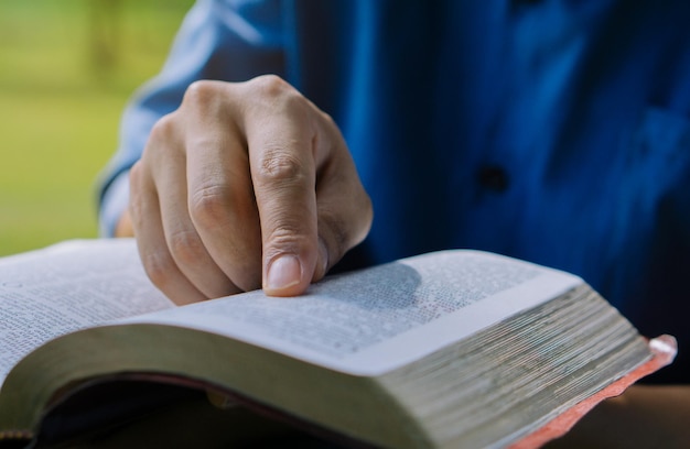 Foto close up mão de oração jovem sentado ao ar livre para ler a bíblia e adorar deus