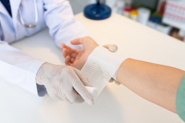 Close-up mão usar luvas médicas do médico mão amarrar atadura na mão do paciente na clínica, osteófitos e calcanhar, fáscia