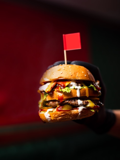 Foto close-up mãos segurando saboroso hambúrguer de carne grelhada com alface e maionese. grupo de jovens comendo em fast food. amigos passando um tempo juntos em um café, um bar de cerveja ou um bar.