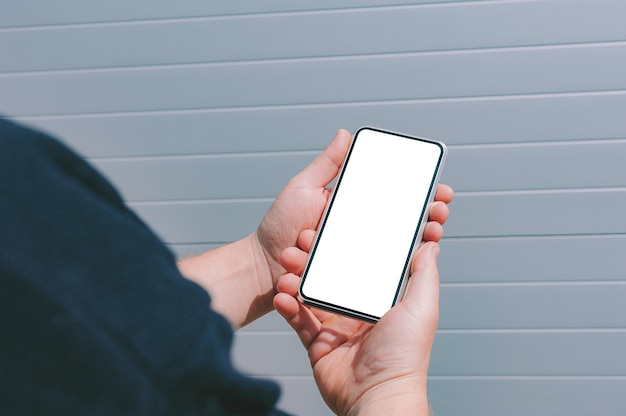 Close-up, maquete de um smartphone nas mãos de um homem. no contexto de uma parede cinza.