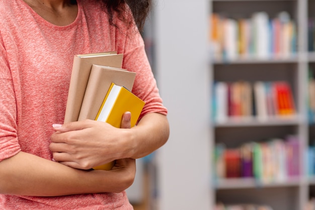 Foto close-up, menina, carregar, pilha livros