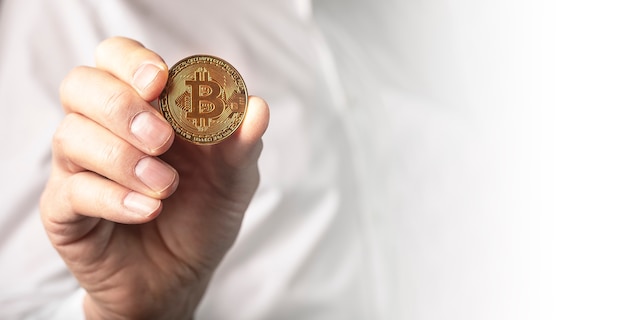 Close-up moeda de ouro bitcoin em mãos masculinas. Banner com espaço de cópia.