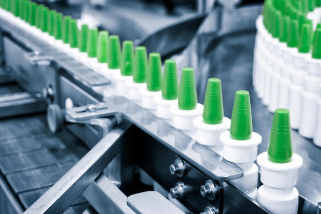 Close-up Muchas botellas de spray de plástico blanco para envasar medicamentos líquidos o cosméticos en una fila en una cinta transportadora en una fábrica de fabricación farmacéutica