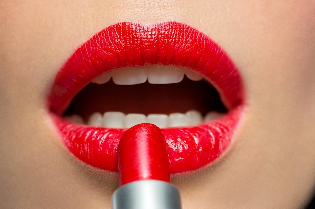 close up de una mujer aplicando lápiz labial rojo a los labios