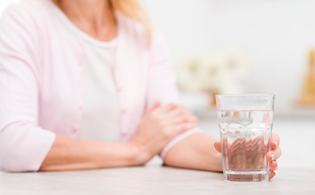 Foto close-up mujer madura sosteniendo un vaso de agua