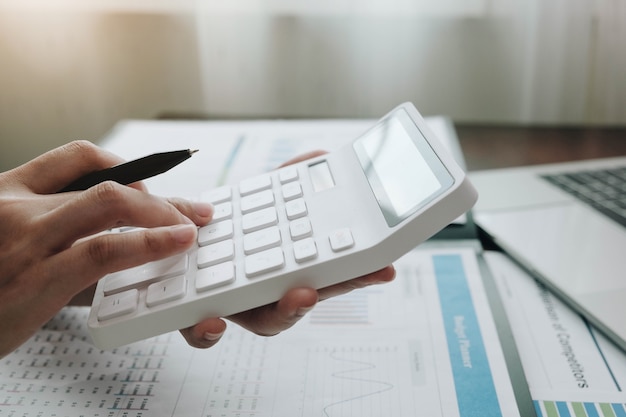 Close-up mulher de negócios usando calculadora e laptop para fazer finanças matemáticas na mesa de madeira no escritório e negócios trabalhando, impostos, contabilidade, estatísticas e conceito de pesquisa analítica