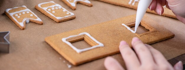 close up mulher está decorando biscoitos de gengibre de Natal