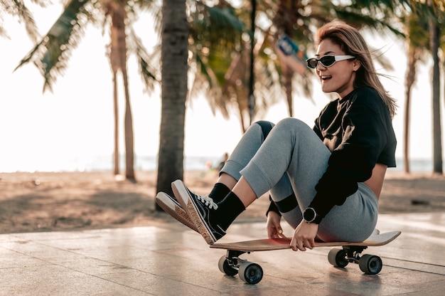 Close-up Mulheres asiáticas surfam skate ou patinam ao ar livre em um lindo dia de verão