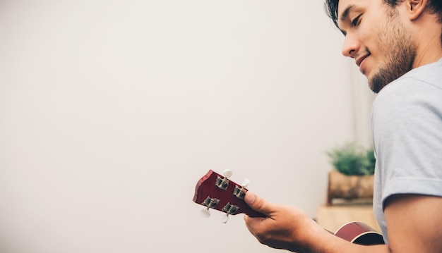 Foto close up music man está tocando ukulele no conceito de estilo de vida da sala de estar