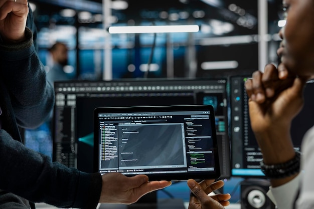 Close up of programmers coding on tablet in data center refining algorithms
