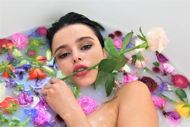 Close-up-Porträt einer Frau, die mit Blumen in der Badewanne badet