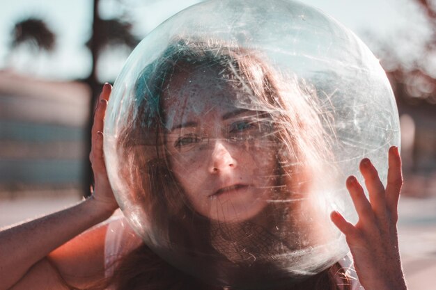 Foto close-up-porträt einer jungen frau, die an einem sonnigen tag einen glashelm auf dem kopf trägt