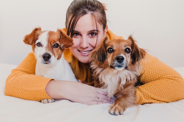 Close-up-Porträt einer lächelnden jungen Frau mit auf dem Bett liegenden Hunden