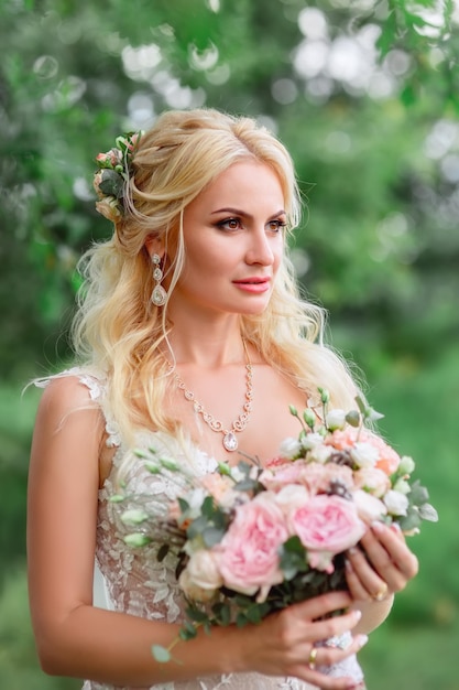 Close-up-Porträt einer schönen Braut in einem weißen Hochzeitskleid mit einem Blumenstrauß im Freien