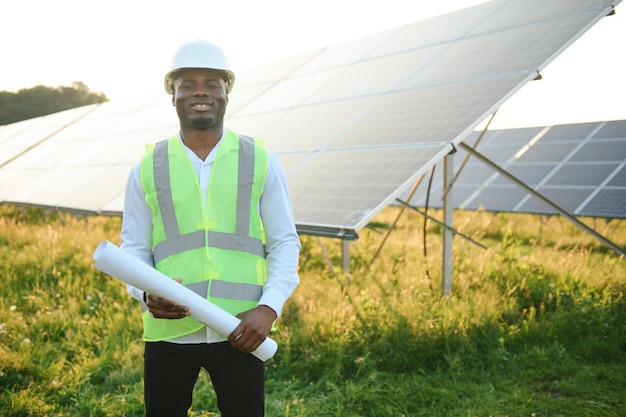 Close-up-Porträt eines jungen afroamerikanischen Ingenieurarbeiters in Hardhat, der einen Solarplan hält, ein zukünftiges Konzept für grüne Elektrizität