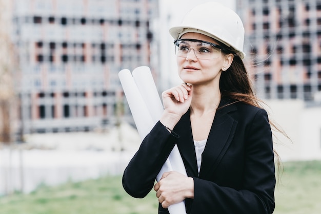 Close up Portrait der schönen Mädchen in einem gelben Schutzhelm und Schutzbrille, ein architektonisches Konzept