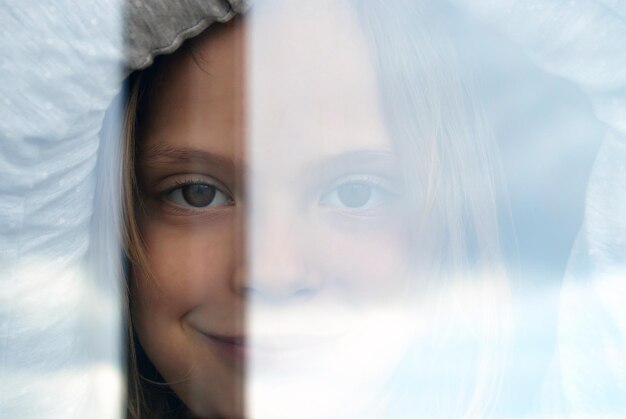 Close-up-Portrait eines Mädchens, das durch das Fenster schaut