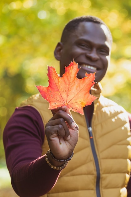 Close up Portrait von afroamerikanischen Mann gibt Herbst Ahornblatt Herbstnatur Saisonale Herbstmode