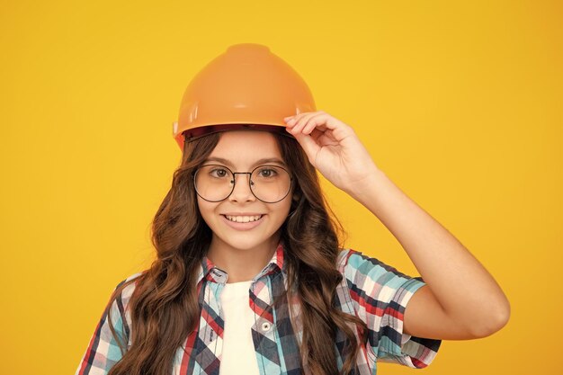 Close up Portrait von Teenager Kind Builder in Helm Teenager-Mädchen auf Reparaturarbeiten isoliert auf gelbem Hintergrund