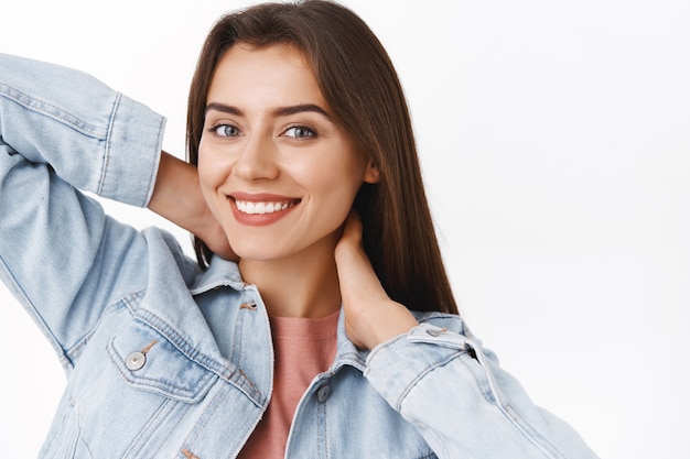 Foto close-up, relaxada, despreocupada linda mulher morena feminina tocando o pescoço suavemente e sorrindo