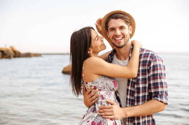 Close Up retrato de una feliz pareja joven inconformista en el amor de pie en la playa y abrazar