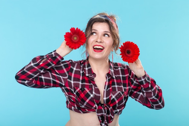 Close-up retrato de una hermosa joven sosteniendo flores rojas con diferentes corazones en las manos