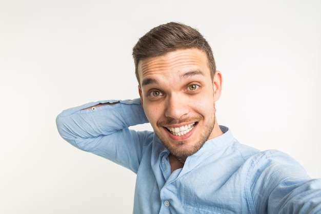 Close up retrato de un hombre barbudo alegre tomando selfie sobre fondo blanco.