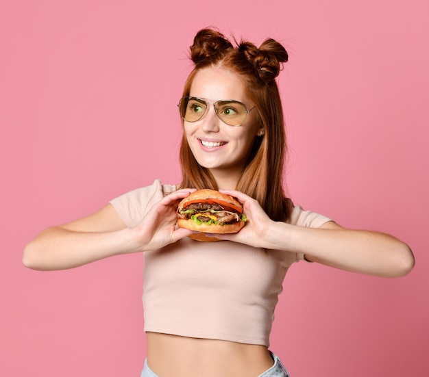 Close Up retrato de una joven hambrienta comiendo hamburguesa aislado sobre fondo blanco.