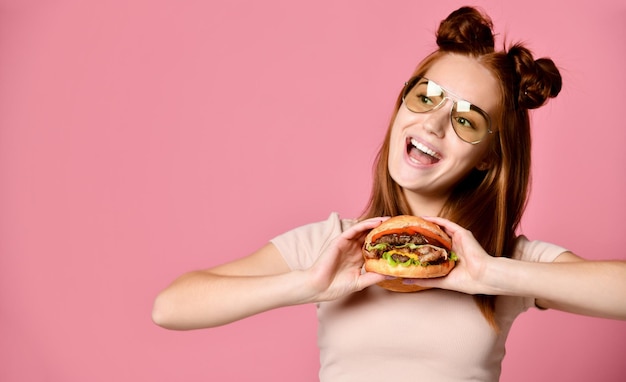 Close Up retrato de una joven hambrienta comiendo hamburguesa aislado sobre fondo blanco.