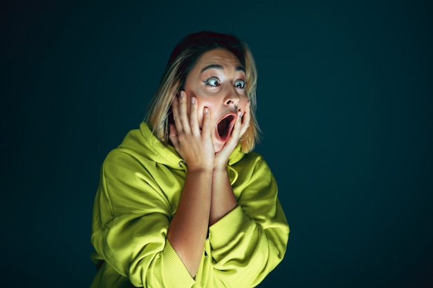 Foto close up retrato de joven loca asustada y conmocionada aislada sobre fondo oscuro