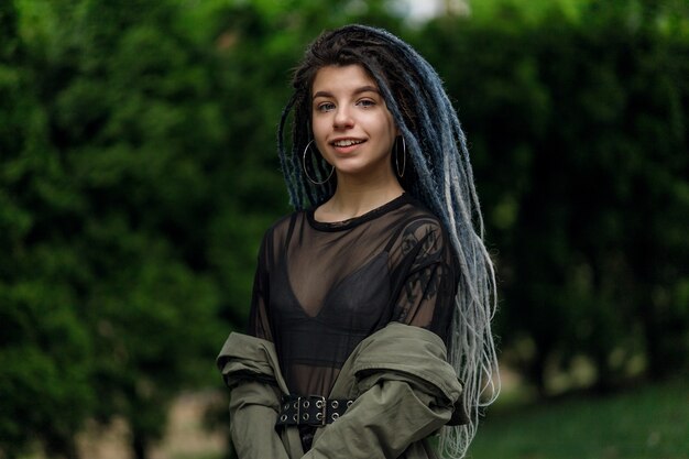 Close Up retrato de una joven mujer muy sonriente con rastas, alegremente mirando a la cámara caminando en la ciudad