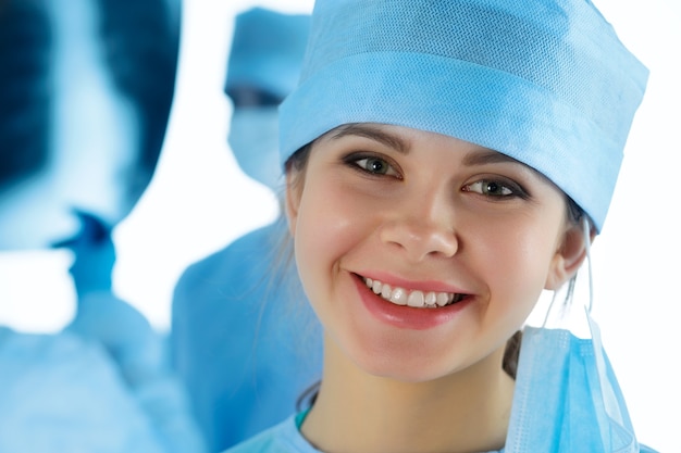 Close Up retrato de joven sonriente médico cirujano rodeado por su equipo