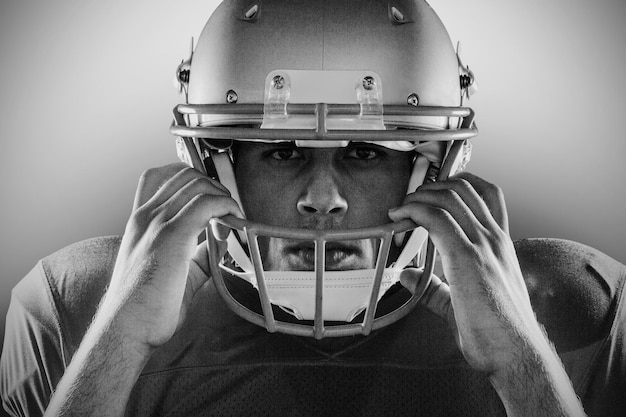 Close-up retrato de jugador de fútbol americano con casco contra fondo negro