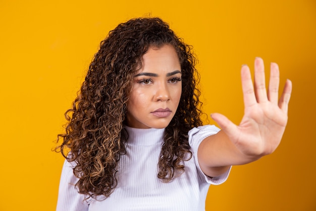 Close Up retrato de una mujer africana joven seria mostrando gesto de parada con su palma aislada