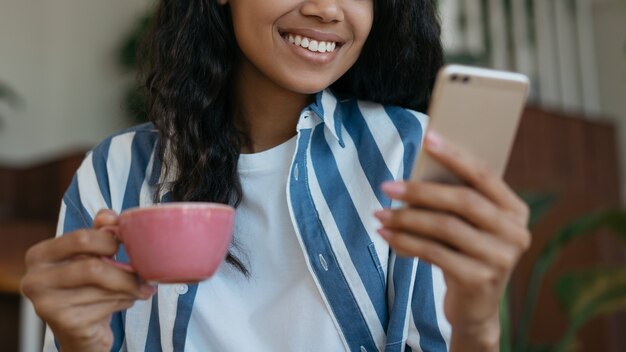 Close Up retrato de mujer africana sonriente mediante teléfono móvil