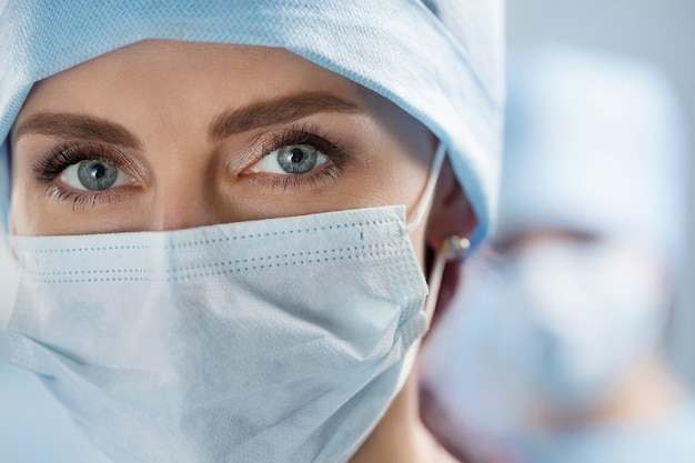 Close Up retrato de mujer médico cirujano con gorra y máscara protectora