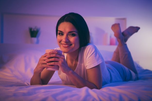 Close-up retrato de mujer soñadora acostada en la cama relajarse mantenga taza