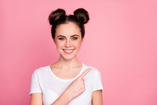 Close-up retrato de niña alegre señalando el pulgar mostrando un anuncio aislado sobre fondo de color rosa