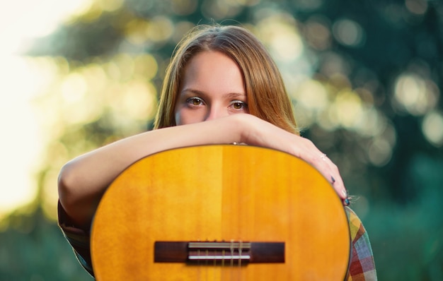 Close Up retrato de una niña músico con una guitarra acústica de madera