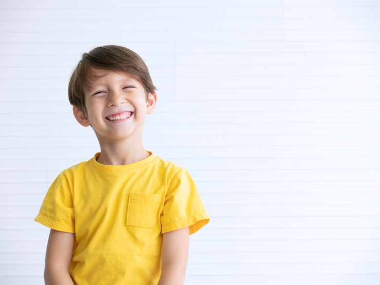 Foto close up retrato de un niño feliz sonriendo sobre fondo blanco.