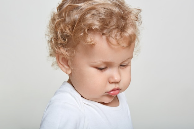 Close Up retrato de niño mirando a otro lado, el bebé tiene el pelo rubio y rizado, vistiendo camisa casual