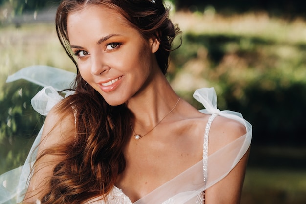 Close-up retrato de una novia elegante con un vestido blanco en la naturaleza en un parque natural.Modelo en un vestido de novia y guantes. Bielorrusia