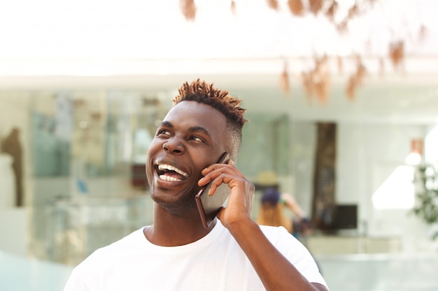 Close-up rindo jovem Africano falando no telefone móvel e olhando para longe