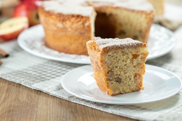 Close up Stück Biskuit oder Chiffon-Kuchen mit Äpfeln so weich und lecker geschnitten mit Zutaten Zimt Eier Mehl Äpfel auf Holztisch Hausbäckerei Konzept für Hintergrund und Tapete