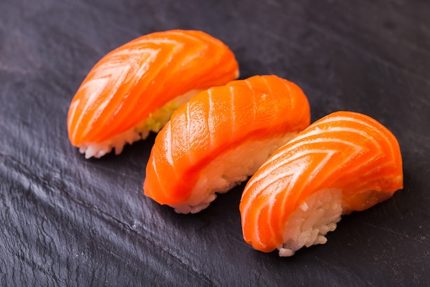 Close-up de sushi sake con salmón sobre un fondo de pizarra negra