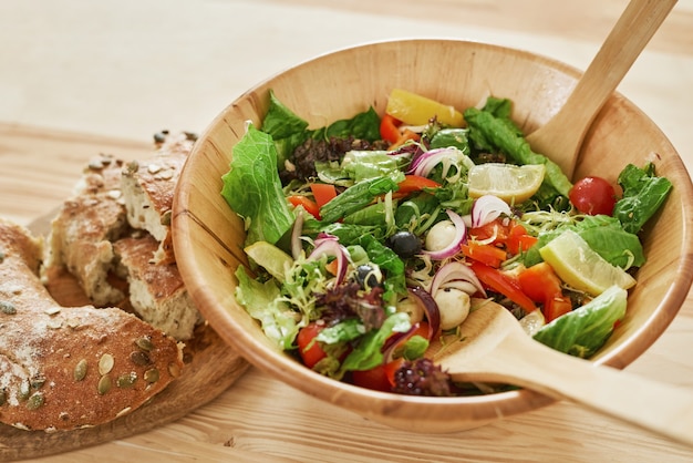 Close-up de tazón con ensalada de verduras y pan fresco sobre la mesa