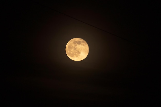 Close-up tiro da lua cheia contra o céu noturno preto escuro Cidade de fios elétricos à noite