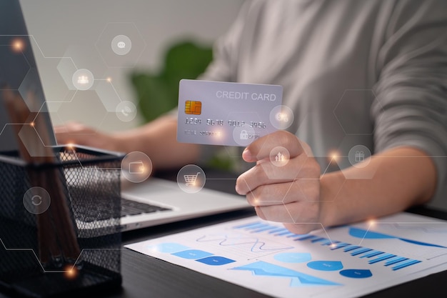 Close-up tiro de mãos femininas segurando uma mensagem de digitação de cartão de crédito no laptop para fazer compras on-line com ícones de tecnologia
