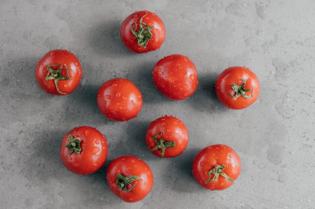 Close-up tiro de tomates da herança vermelha cravejados com gotas de água contra fundo cinza Legumes frescos Tiro horizontal