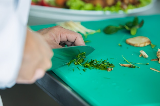 close-up tiro de um chef cortar legumes em comida Vai cozinhar na cozinha para servir comida para os clientes no restaurante do hotel